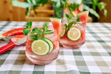 Summer refreshing watermelon drink with ice, mint and slices of lime on the table. Fresh healthy cold melon beverage. Fruit infused water, herbs and lemon. © Caterina Trimarchi