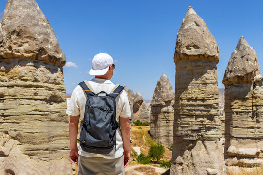 Traveler exploring Love valley rock formations in Cappadocia with backpack. Adventure, hiking, tourism, discovery, freedom, and outdoor lifestyle concept.