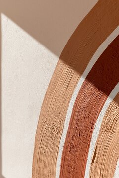 Hand-painted terracotta and dusty ochre mural detail with textured brush strokes on a matte wall in a boho-style nursery setting