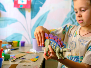Close up of a boy's hands manipulating a plastic Stegosaurus toy while making roaring sounds. Active imaginative play and childhood storytelling. © light