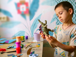 Curious young boy closely examining a toy dinosaur upside down. Childhood discovery, learning, and imaginative play at home © light