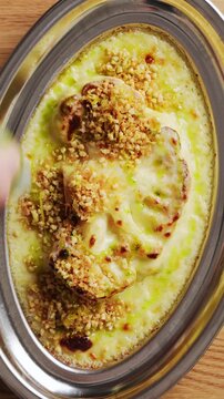 Chef drizzles green oil over roasted cauliflower in cheese sauce. Roasted cauliflower, topped with toasted nuts, makes elegant, healthy restaurant side dish. Roasted cauliflower cooks easily at home.