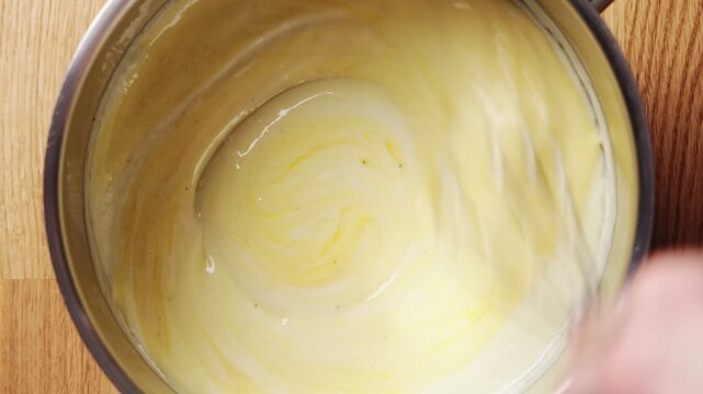 Whisk stirs egg yolk into sauce, creating smooth golden color. Egg yolk sauce technique resembles classic hollandaise for brunch dishes. Silky egg yolk sauce turns eggs benedict into bistro favorite.