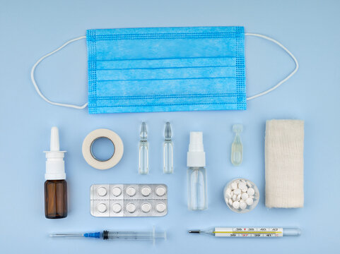 Medical supplies and medicines on blue background, flat lay with pills, syringes, ampoules, thermometer and nasal spray. Healthcare, treatment and pharmacy concept