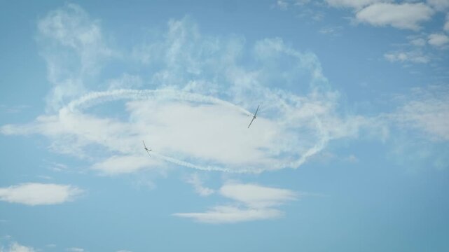 Airplane performing circular aerobatic maneuver with smoke trail in cloudy sky
