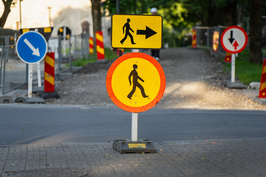 Temporary yellow and orange roadworks traffic signs indicating pedestrian path detour and route modification rules for public infrastructure safety