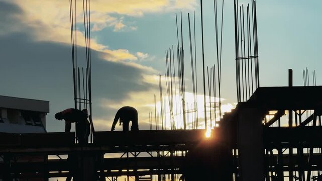 Dedicated Construction Team Silhouetted at Sunset Building Site