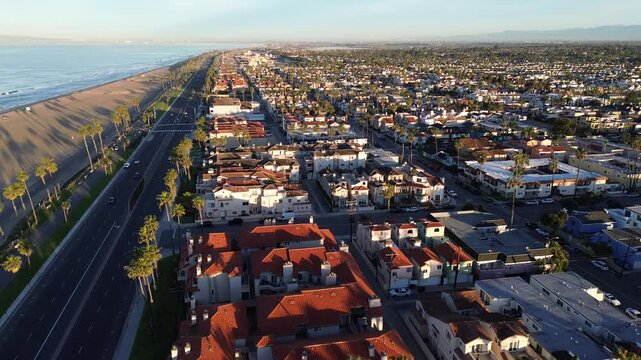 Elevated viewpoint highlights luxury coastal real estate high end properties in Huntington Beach, CA. Pacific Coast Highway PCH runs parallel to upscale beachfront housing with scenic ocean views