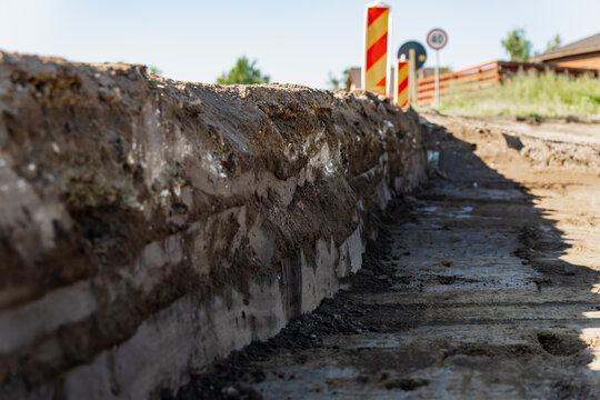 Layered soil cross section and excavated ground levels on a roadbed development site prepared for paving and utility installation