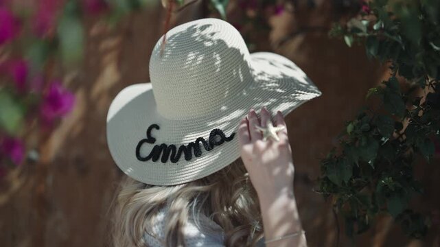 Woman in straw hat with 'Emma' name in Sidi Bou Said garden