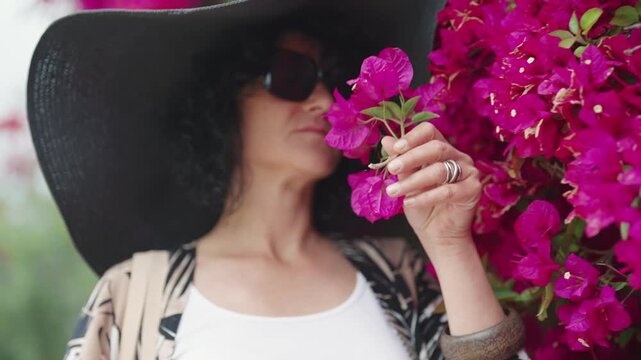 Fashionable Woman Smelling Pink Flowers in Sidi Bou Said, Tunisia