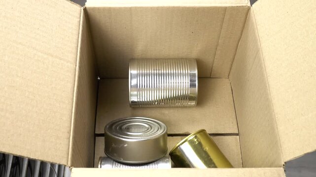 Different empty metal food cans are placed in a cardboard box Disposal and recycling of metal containers