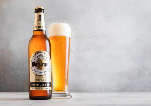 LONDON,UK - APRIL 12, 2026: Bottle and glass of Warsteiner gold lager beer on light table background.
