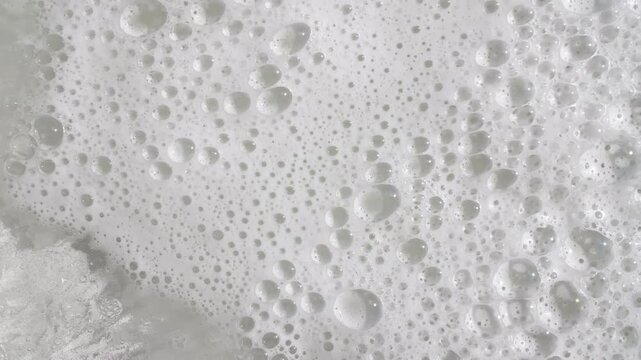 Texture of white soap foam with bubbles abstract background. Soap sud macro structure. Bathtup Soap Foam. Natural White Shampoo Bubbles Motion. High quality 4k footage