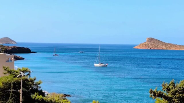Panoramic view of the choppy sea in Myrties, Kalymnos, Greece. A sailboat and a motorboat in the distance. In the background, the island of Telendos