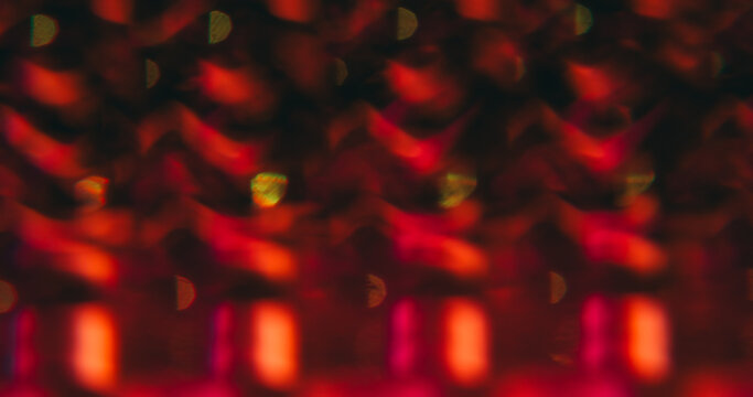 Patterned effect. Blur lens gleam. Defocused red pink color flare flicker sparkle glimmer shine on abstract bokeh light art dark black background.