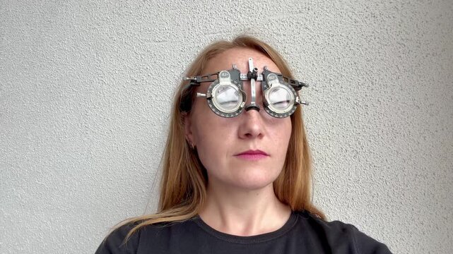 Young woman wearing optometry trial frame for vision exam looking around