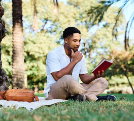 Fototapeta premium Young man student businessman enjoys sunny day while reading a book in park, highlighting his joy and connection to the world around him