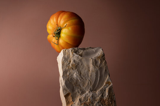 Pomodoro costoluto maturo in equilibrio su pietra naturale, natura morta minimalista con spazio per il testo
