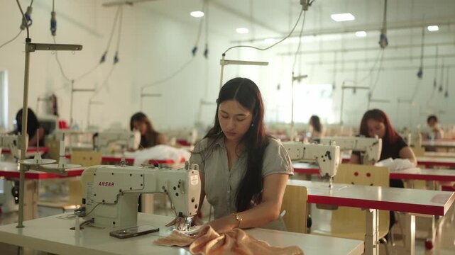 Group of fashion students working together in busy design workshop with sewing machines and mannequins in background