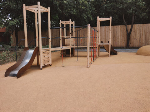 A modern, safe playground in a park with rubber surfacing made from recycled materials. Shock-absorbing rubber flooring in a public park.