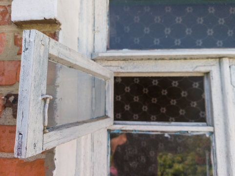 Open old white wooden window frame on brick wall