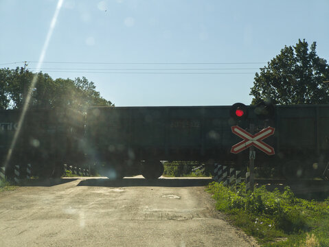 Railway crossing with a freight train passing by slowly