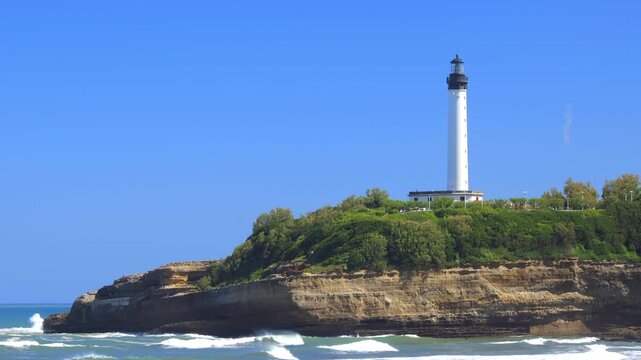 Panoramic view of the Biarritz Lighthouse atop the rocky headland of Pointe Saint-Martin under a blue cloudless sky
