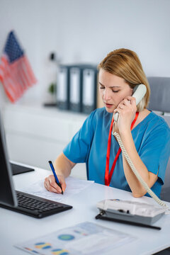 Healthcare professional talking on phone taking notes at desk