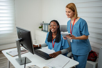 Diverse medical workers collaborating on computer and digital tablet © Jelena