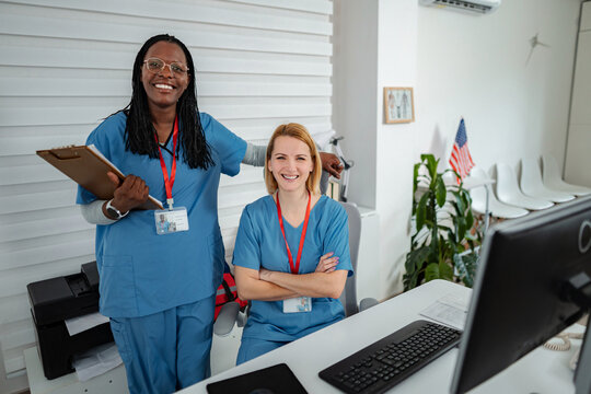 Diverse nurses standing together smiling in medical reception area