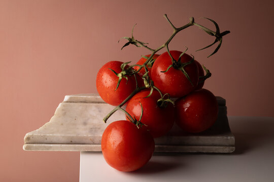 Pomodori rossi maturi a grappolo su elemento di marmo e base bianca, natura morta con spazio per il testo