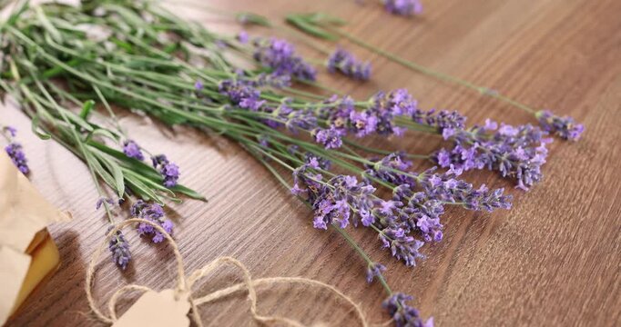 Fresh lavender bouquet lying on dark wooden table background. Paper gift tag with twine string near plant stems. Countryside botanical harvest layout template with large copy space.