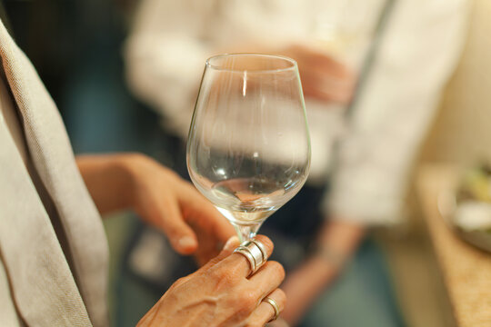 Hand holding empty wine glass indoors with people visible