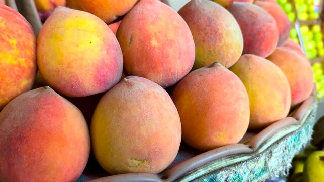 Ripe Peaches Stacked: A vibrant display of ripe peaches, with their fuzzy skin and warm hues, are artfully arranged in a rustic market stall, promising a taste of summer's sweetness.