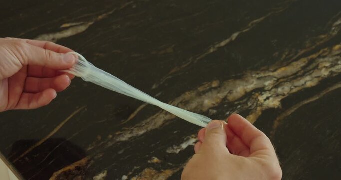 Person stretching a condom with both hands to test flexibility, durability and protection quality.