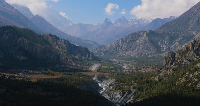 Annapurna Circuit, Humde, Manang, Nepal, aerial landscape shot revealing the mountain airport runway in a deep pine forest valley near the Marsyangdi River bed.