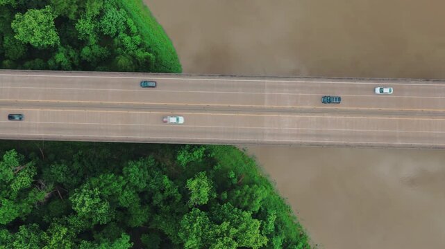 Freight truck vehicles keep the supply chain moving across the Atchafalaya wetlands. This overhead drone shot captures a flatbed hauling a covered load on the I-10 Louisiana elevated bridge.
