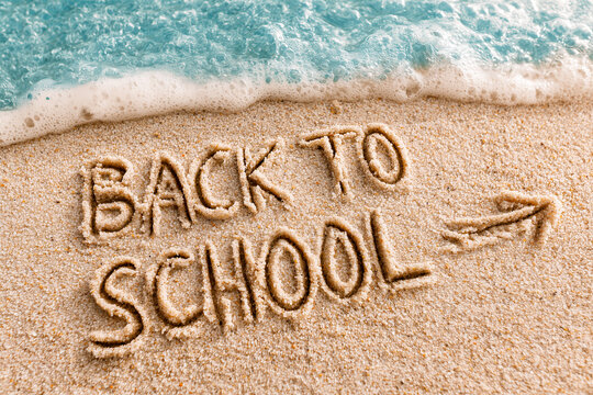 Text Back to school written in the sand of the beach, end of summer vacations concept in august or september