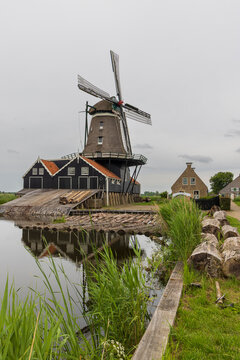Historic saw windmill by a canal in IJlst Friesland Netherlands reflecting traditional Dutch rural life and tourism appeal