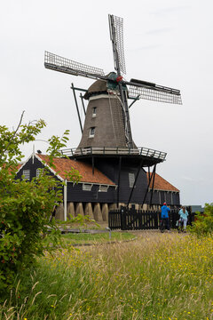 Historic saw windmill by a canal in IJlst Friesland Netherlands reflecting traditional Dutch rural life and tourism appeal