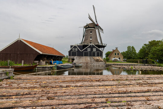 Historic windmill by a canal in IJlst Friesland Netherlands reflecting traditional Dutch rural life and tourism appeal