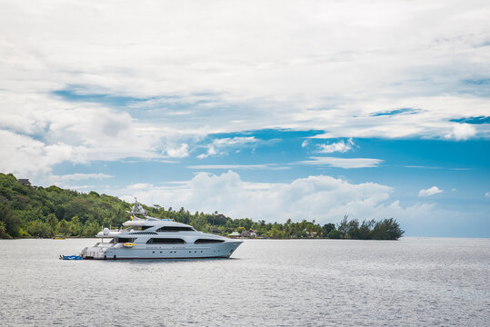 Charter motor yacht at anchor in Cook's Bay, Moorea, French Polynesia on a sunny day with blue sky, with inflatable water toys on the stern