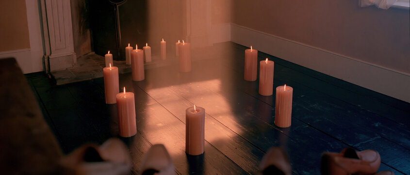 Glowing beeswax candles on a dark wooden floor create a warm amber light pattern in a cozy room, perfect for seasonal Sinterklaas holiday backgrounds