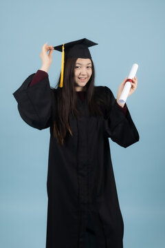 Proud graduate girl in academic gown raising her rolled diploma cert