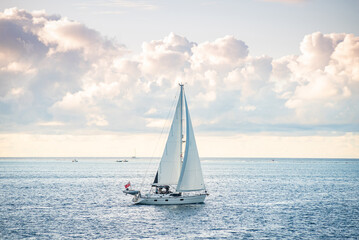 Fototapeta premium Beautiful blue water luxury sailing yacht leaving Cook's Bay, Moorea, French Polynesia, with full sails up, sailing into the horizon close to sunset time