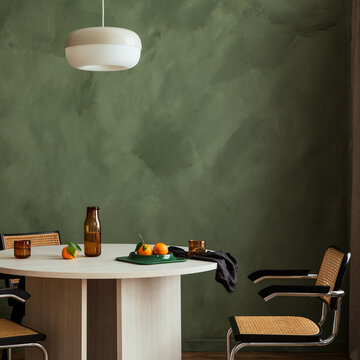 Minimalist Dining Scene with Oranges on a Neutral Table Against a Textured Green Wall and Modern Pendant Light