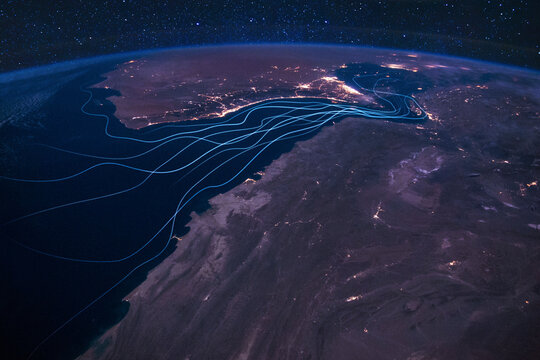 Night orbital view visualizing strategic flow lines through the choke point of the Strait of Hormuz, global tension and potential route disruptions due to regional conflict. transit of oil tankers