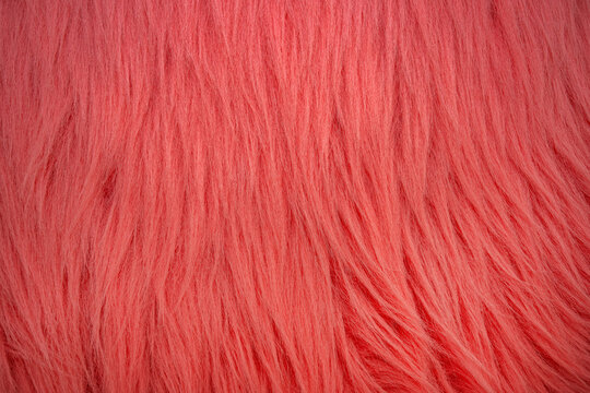 Bright pink fur material with soft texture and flowing strands for crafts and design projects