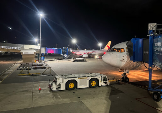 Air Niugini commercial airliner parked on the airfield next to support vehicles during night operations on the tarmac of Jacksons International Airport: 18.07.2026 - Port Moresby, Papua New Guinea